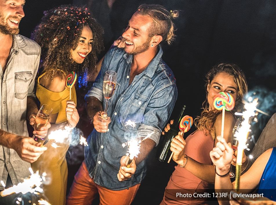 Beach-themed party among friends holding sparklers