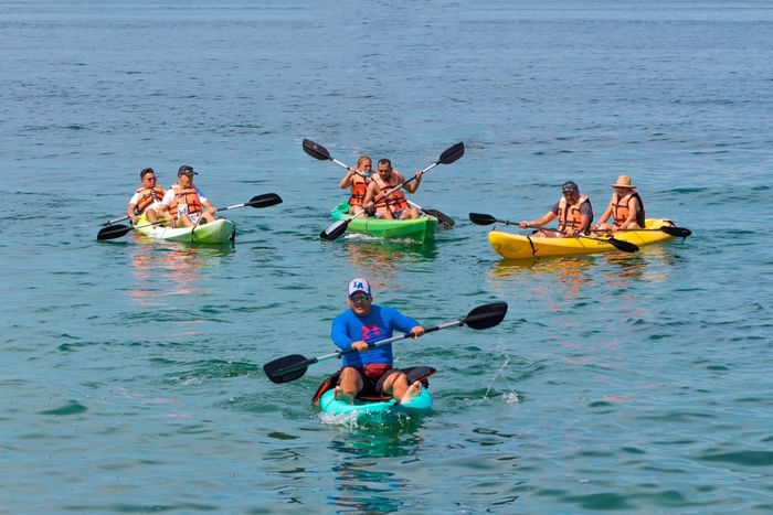 A group of people on kayaks paddling on the water near Plaza Pelicanos Club Beach Resort