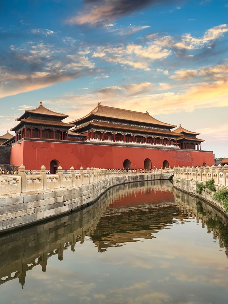 The Forbidden City in Beijing, featuring a grand red palace by a calm moat near Warwick Hotels & Resort