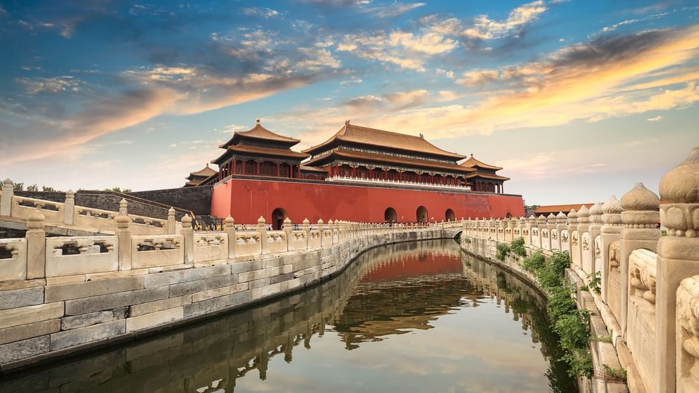 The Forbidden City in Beijing, featuring a grand red palace by a calm moat near Warwick Hotels & Resort