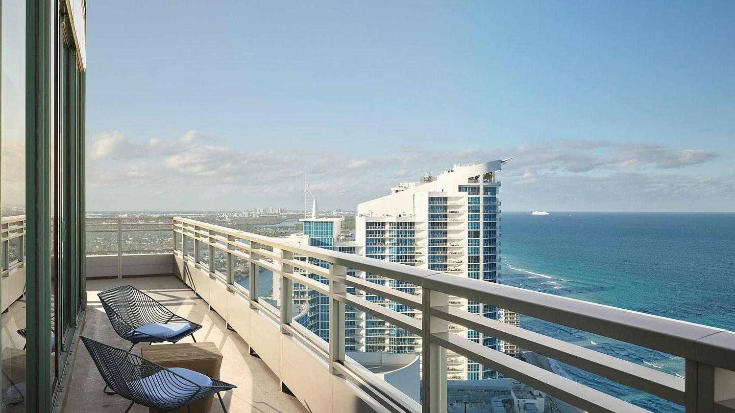 Oceanfront guest room with floor-to-ceiling windows and private balcony.