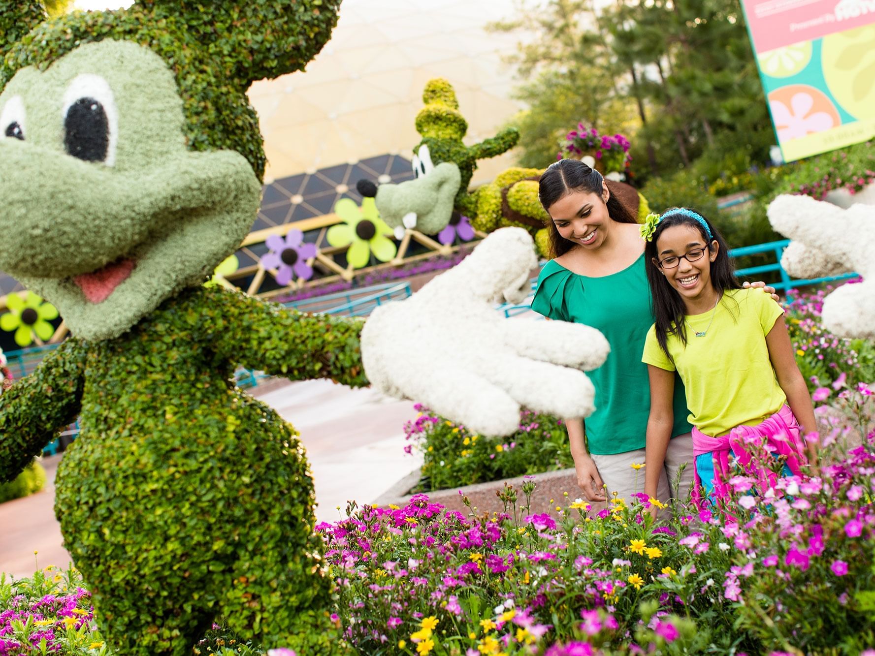 Mother & daughter posing in flower garden featuring shaped plants near Rosen Inn Hotels and Resorts