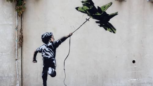 Colorful Banksy art graffiti painting of a boy joyfully flying a kite near Almanac Barcelona