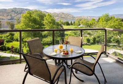 Outdoor patio with dining table, flowers, and scenic mountain view through railings.