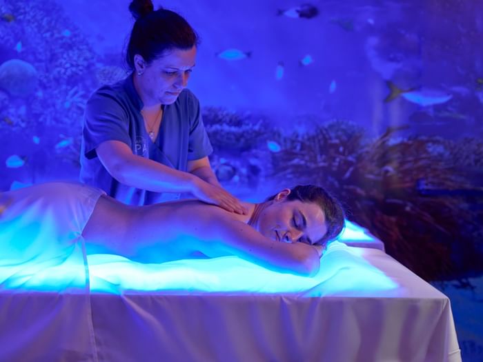 A guest enjoys a relaxing back massage under calming blue light in the spa at Hotel Do Caracol