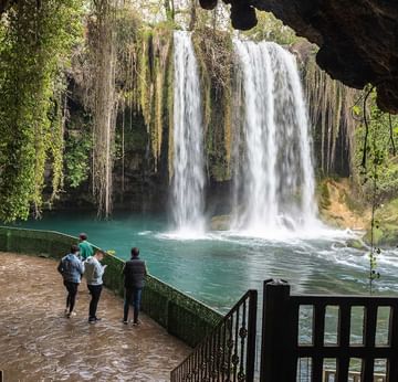 People stand and walk by railings overlooking Duden waterfalls.