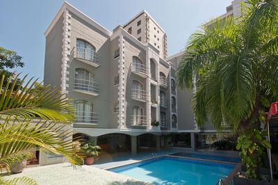 La moderna fachada gris del edificio del Country International Hotel da a una piscina al aire libre rodeada de palmeras.