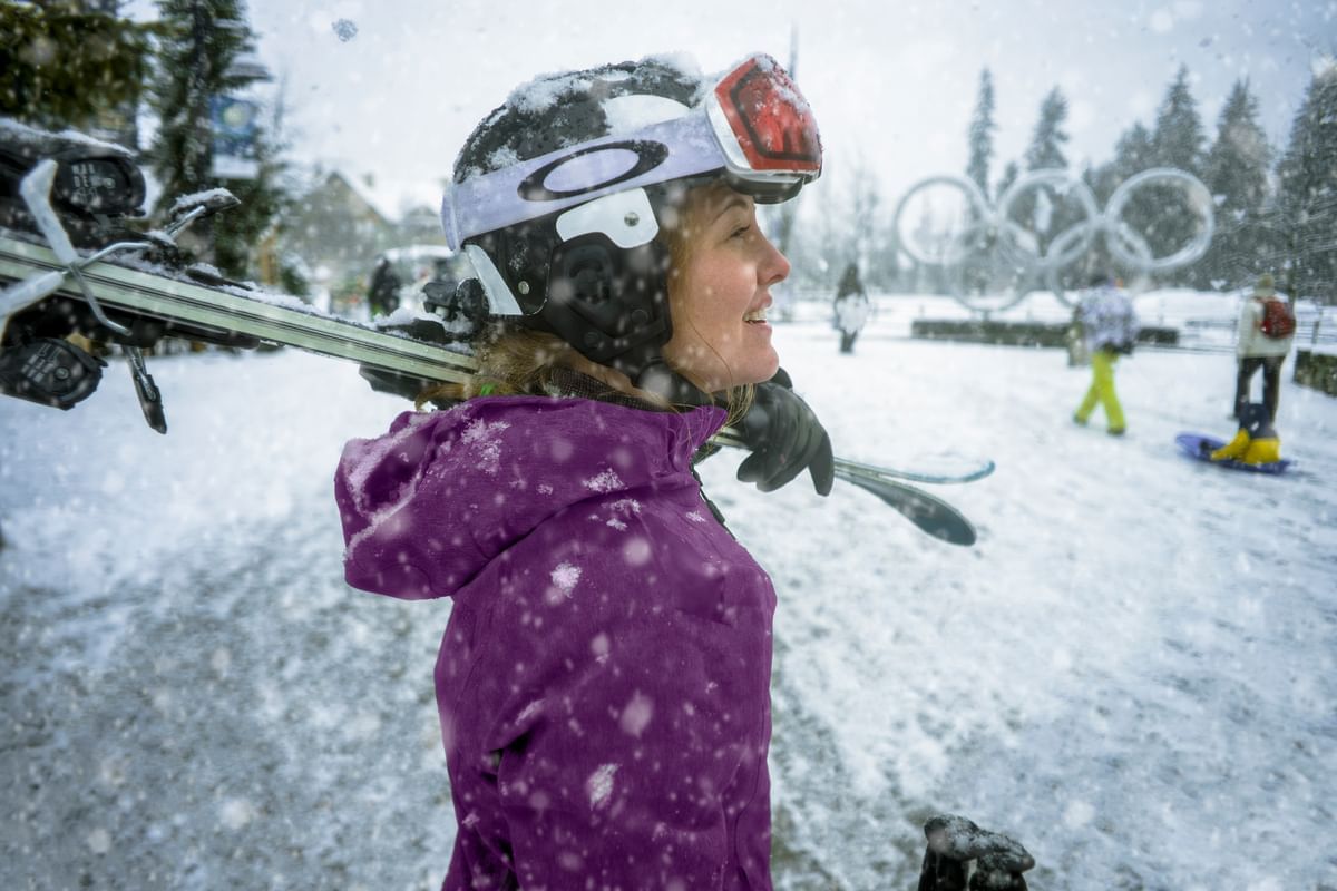 Lady posing by a snow slope with skis near Blackcomb Springs Suites