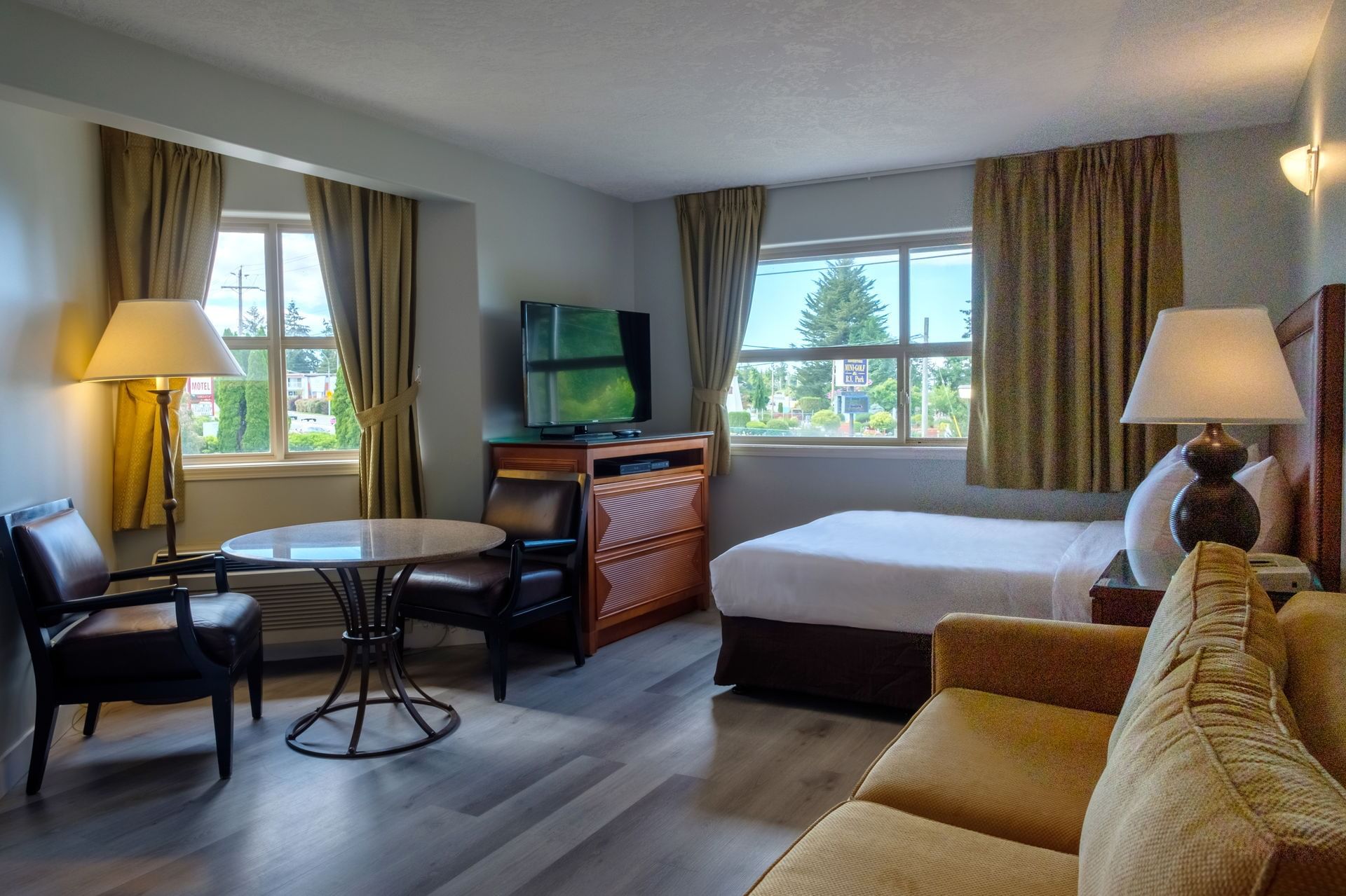 Hotel suite with a big sofa, a table with two chairs and TV