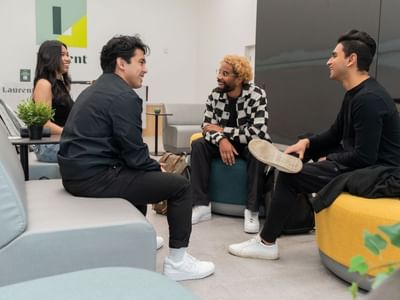 A group of students sit on lounge seating and chat together in a modern student accommodation lobby.