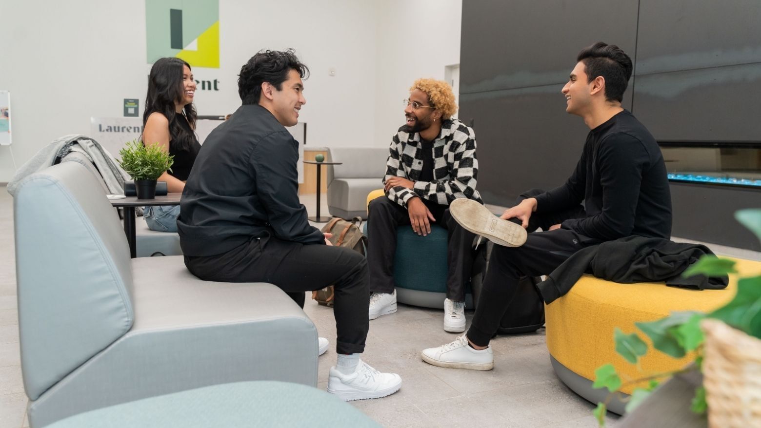 A group of students sit on lounge seating and chat together in a modern student accommodation lobby.