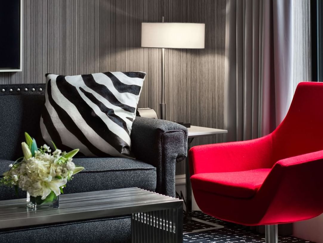 Red mid century modern arm chair and black sofa with zebra print cushion inside a chic hotel room at Moderne in NYC