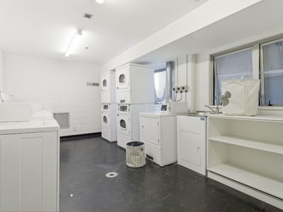 Clean laundry room with washing machines, dryers, and a sink at Student Living Auckland – Anzac.