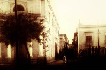 Sepia-toned photo of an old street scene with Historic Hotel El Convento and a person walking.