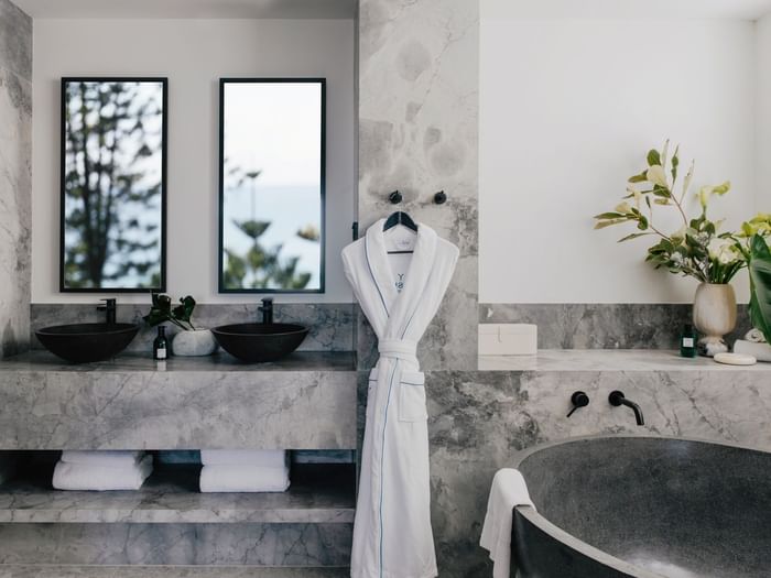 Elysium Suite at Elysium Manly with a black stone tub by twin vessel sinks under mirrors, offering cozy Manly accommodation