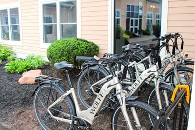 Row of Wolff electric bicycles parked in a bike rack outside the building at Rodd Crowbush Golf & Beach Resor
