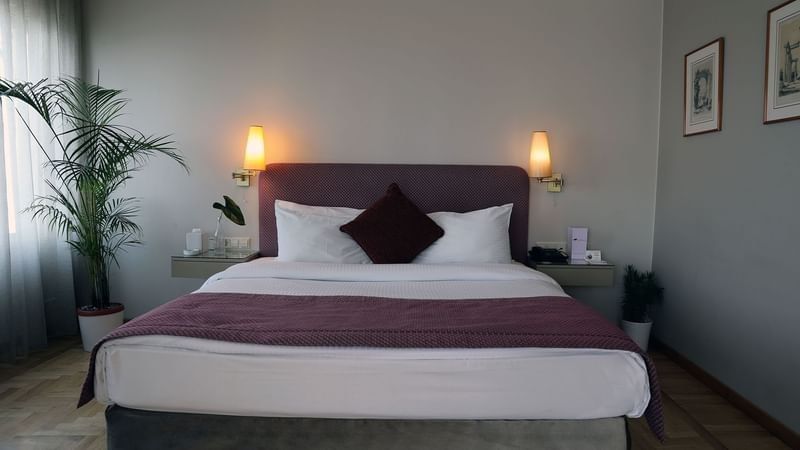 Bed with side tables under hanging wall lamps in Senior Suite at Warwick Palm Beach Hotel