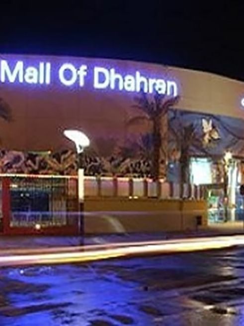 Mall of Dhahran exterior by a street under night lights featuring a large glowing sign near Naviti by Warwick Al Khobar