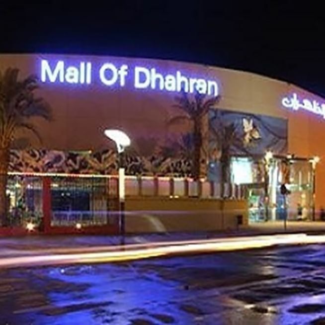 Mall of Dhahran exterior by a street under night lights featuring a large glowing sign near Naviti by Warwick Al Khobar