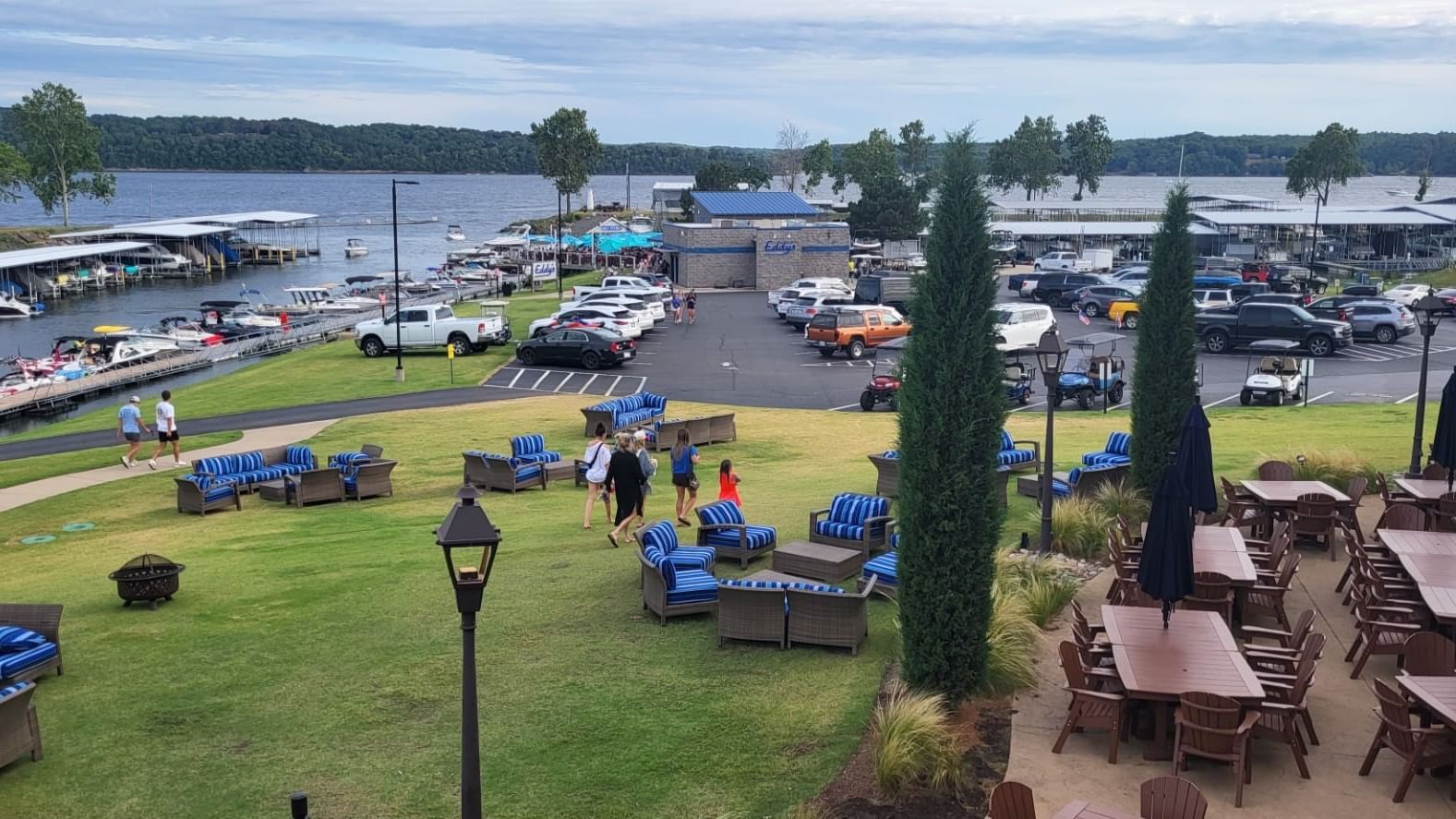 Families walking on grass near blue-striped lounge chairs in Doc's Lower Patio at Shangri-La Monkey Island
