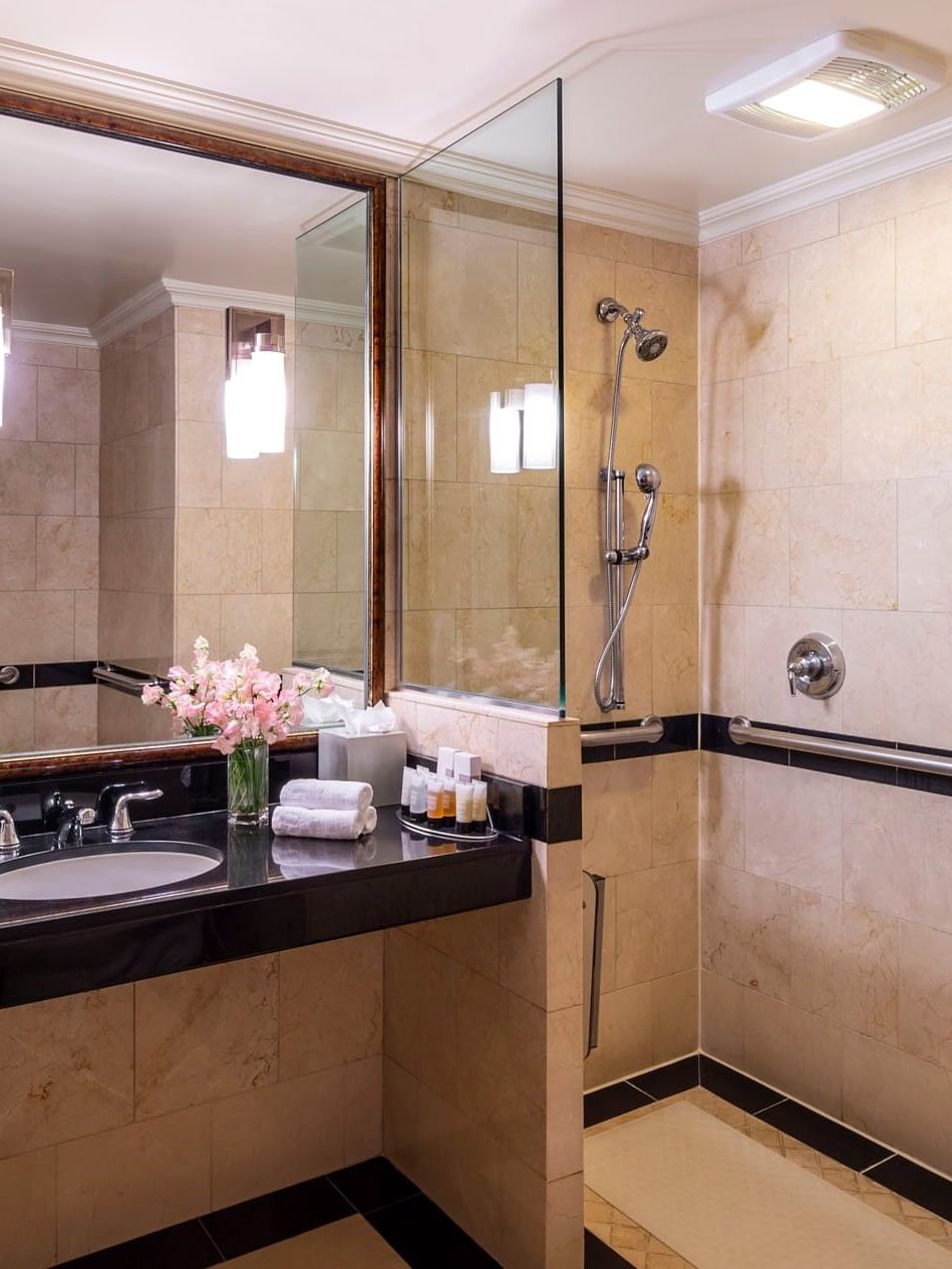 Granite vanity & inset sink, below framed mirror in tiled bathroom in Accessible On the Avenue Suite at Warwick New York