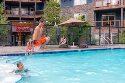 Boy jumping into the pool surrounded by lounge chairs and umbrellas at Blackstone Mountain Lodge