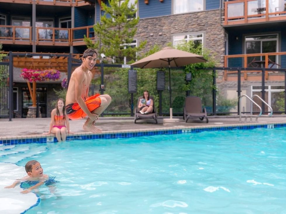 Family lounging and playing by the outdoor swimming pool at Blackstone Mountain Lodge