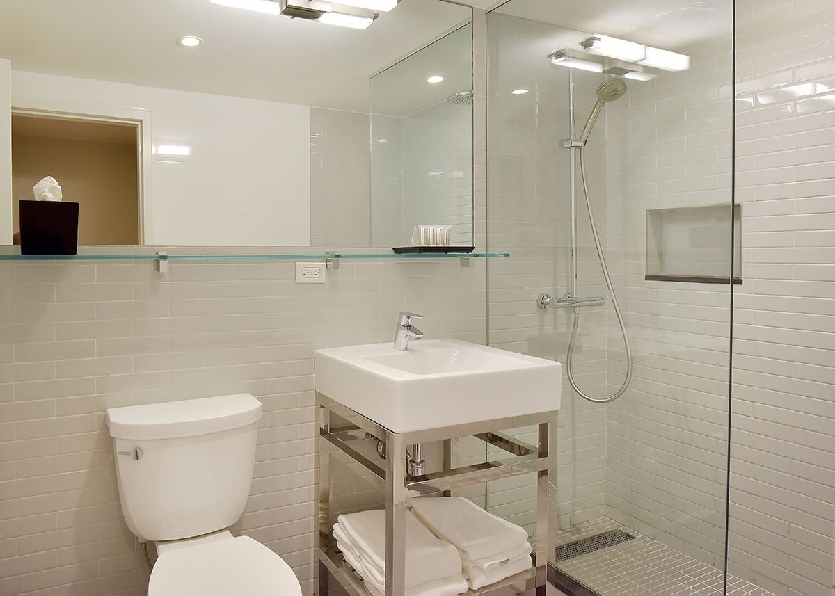 A clean and modern bathroom with a toilet, shower, sink, and mirror.
