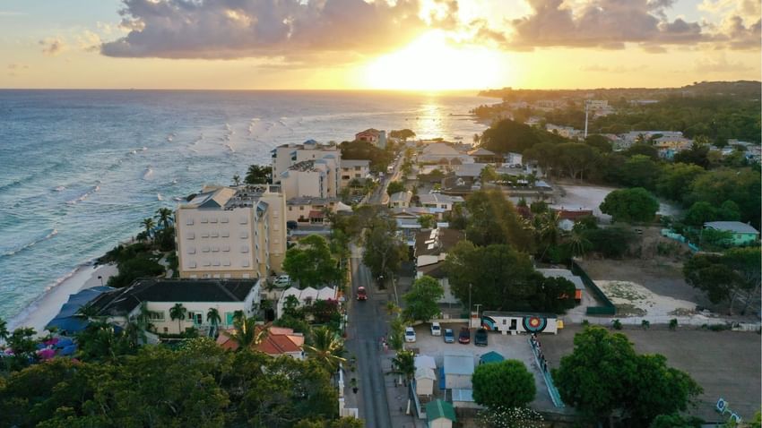 Aerial view of a coastal town by the ocean waves under a vibrant sunset sky, surrounding a street near Time Out Hotel