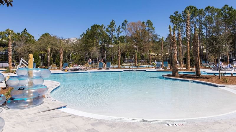 Lounges by the outdoor pool with trees at WaterColor Inn