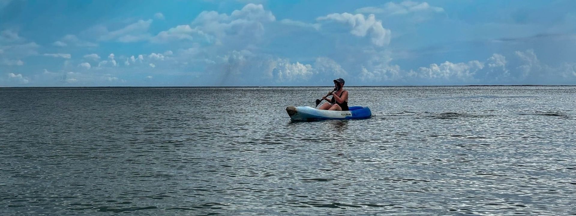 Person kayaking on calm sea under blue cloudy sky at The Naviti Resort in Korolevu