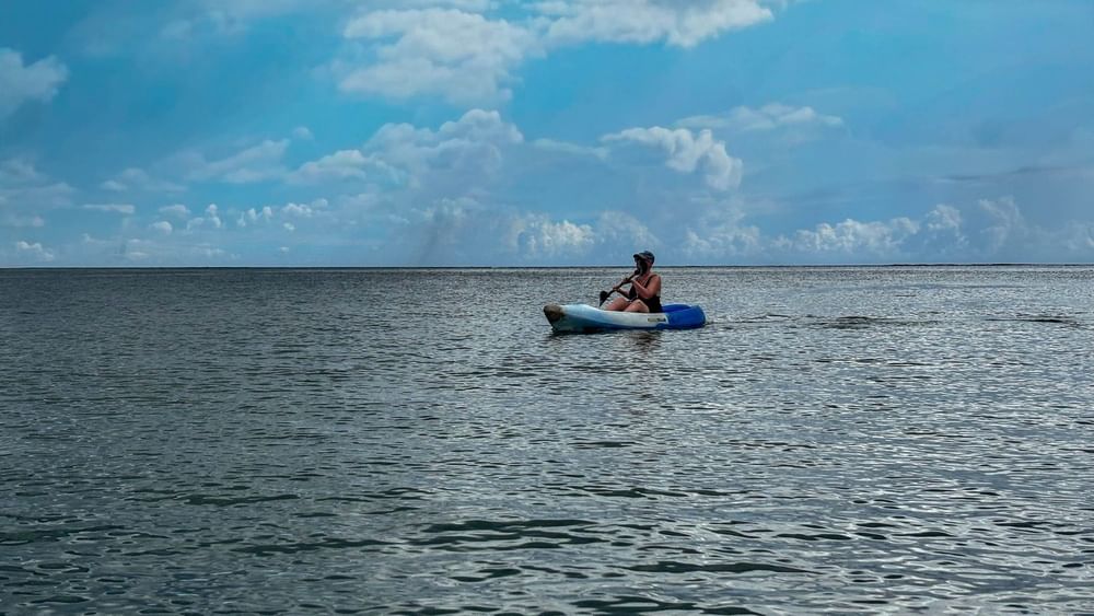 Person kayaking on calm sea under blue cloudy sky at The Naviti Resort in Korolevu.