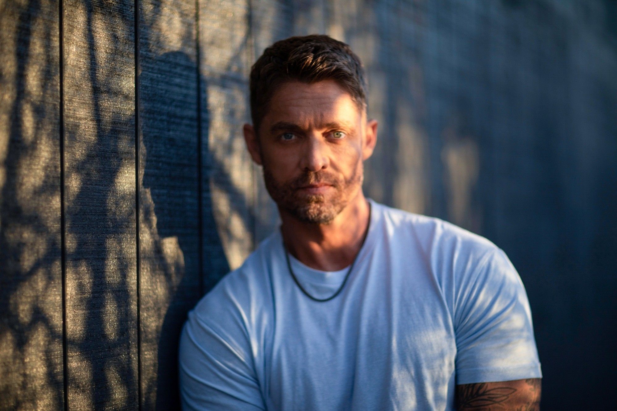 Country music singer Brett Young poses leaning against wall