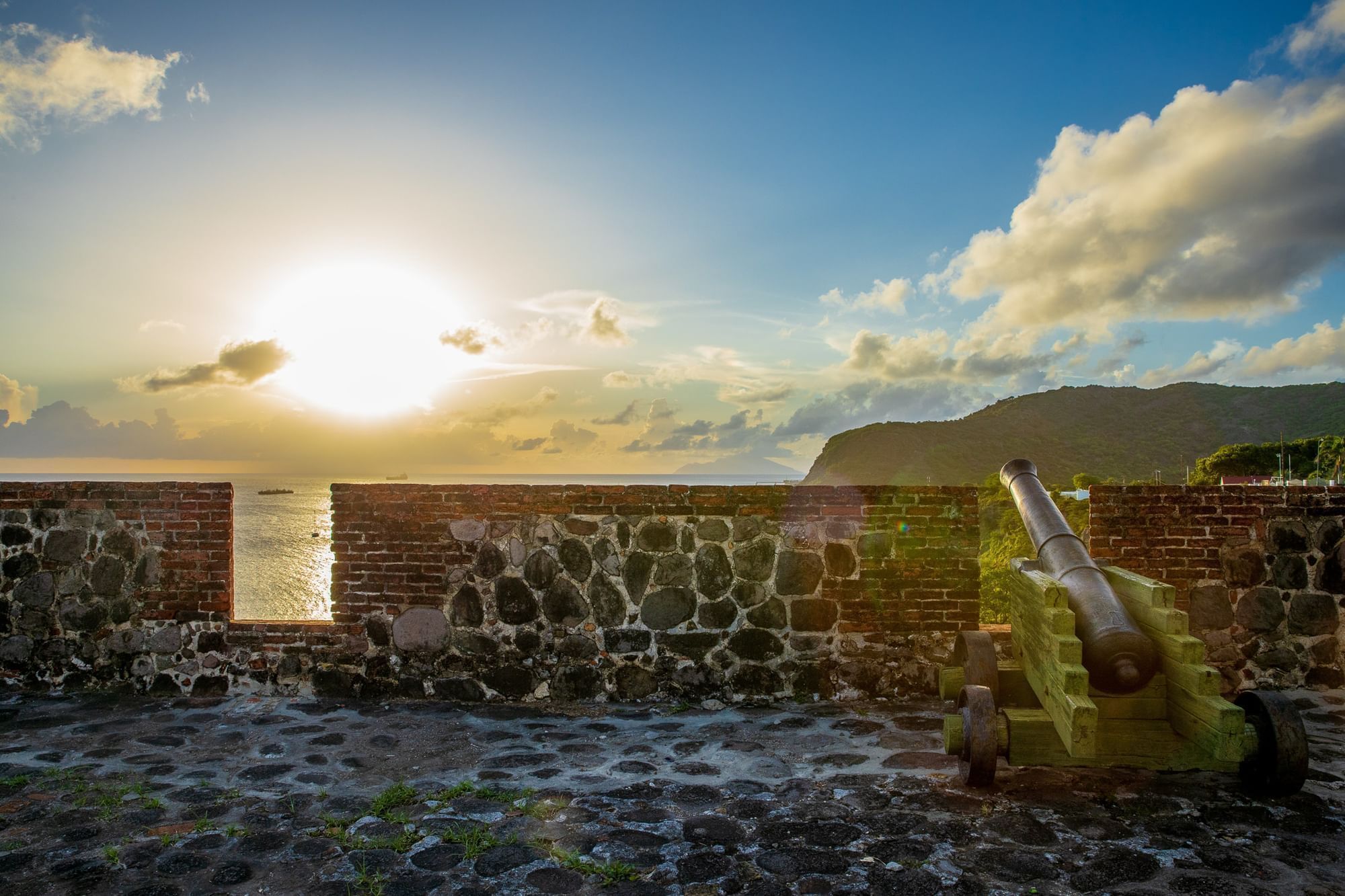 Historic cannon on a stone wall overlooks a sunset over the ocean in Oranje in St. Eustatius near Golden Rock Resort