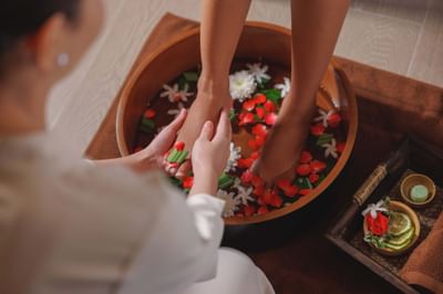 Therapist providing a foot treatment with flower petals and lime slices in LOM Talay Spa at Amora Beach Resort Phuket