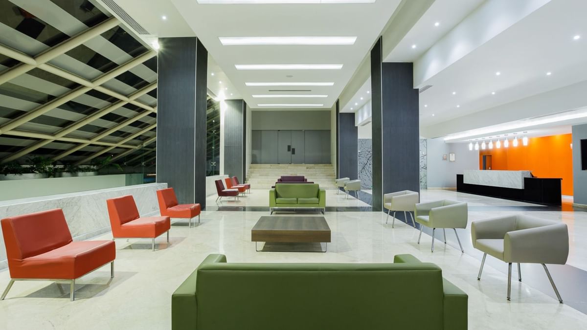 Lobby luminoso con asientos modernos coloridos y recepción de mármol en Real Inn Tijuana