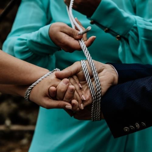 Officiant tying a three cord knot around the couples wrist, a popular African wedding tradition