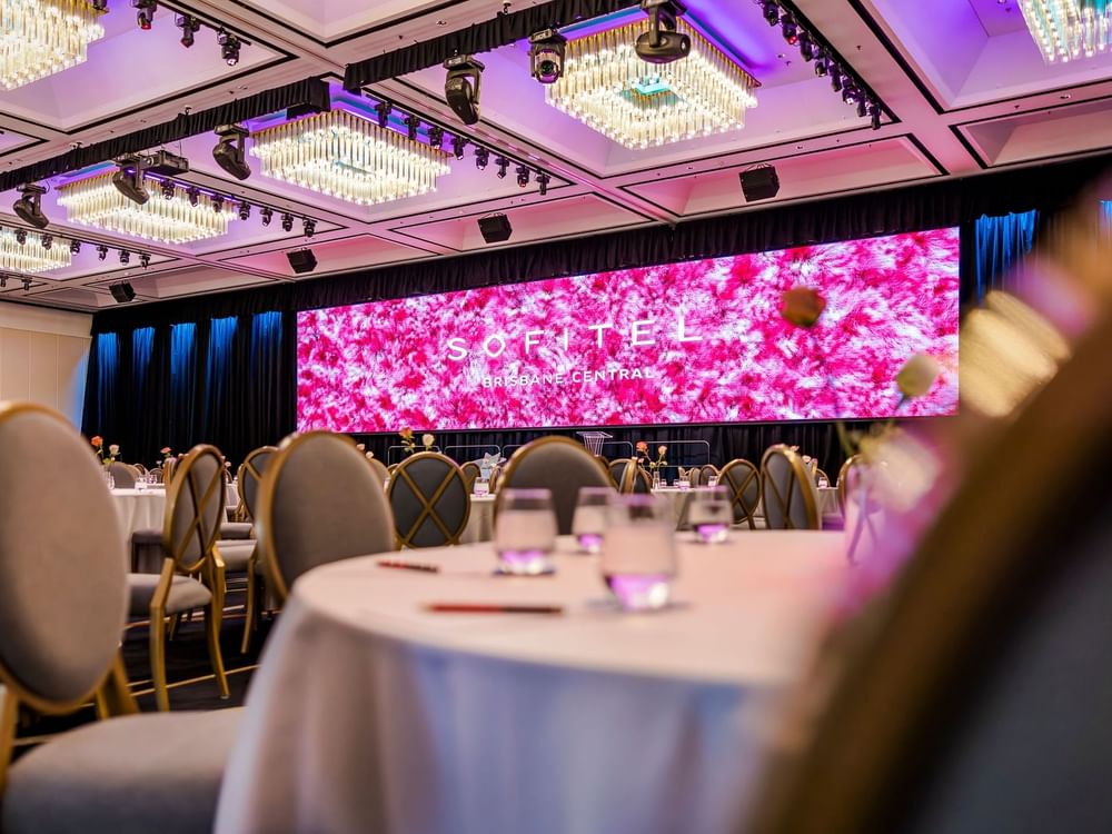 A spacious banquet room featuring elegantly arranged tables and chairs in Ballroom Le Grand at Sofitel Brisbane Central