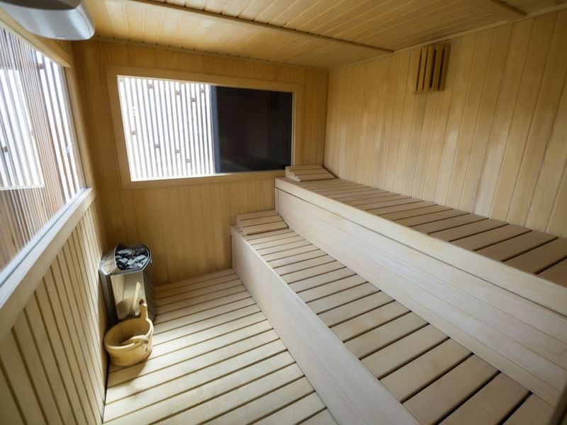 Sauna de madera con ventanas y bancos escalonados en un hotel.