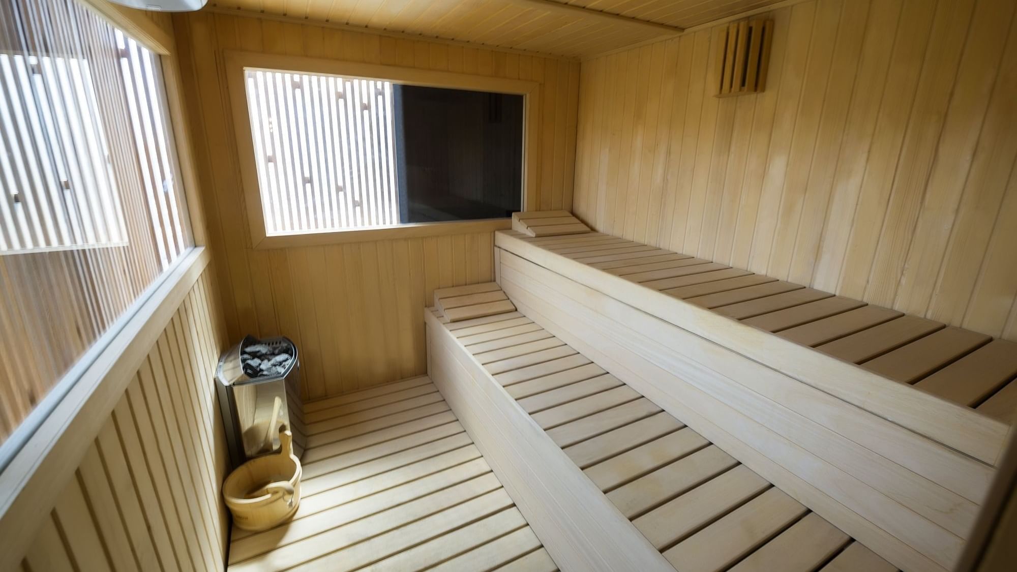 Sauna de madera con ventanas y bancos escalonados en un hotel.