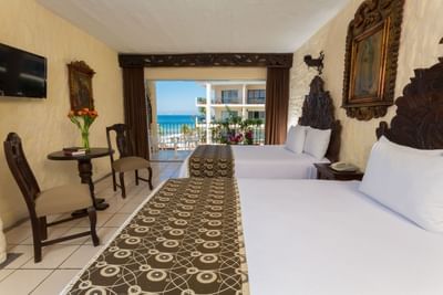 Room with two beds, small table and a balcony