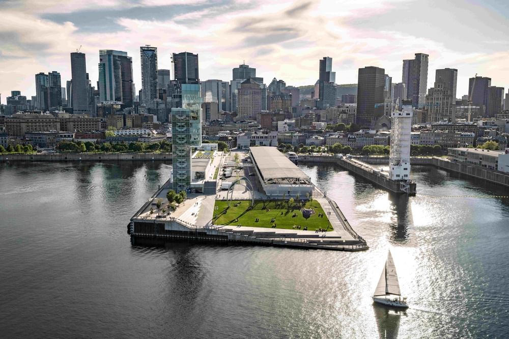 Aerial view of Montreal waterfront with green park pier and sailboat on river at Warwick Le Crystal Montreal