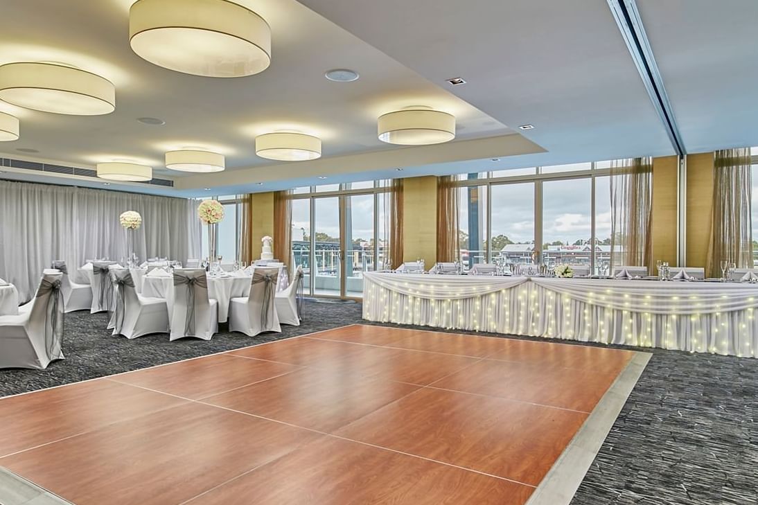 Ballroom wedding setup with dance floor, round tables, and illuminated head table at The Sebel Mandurah
