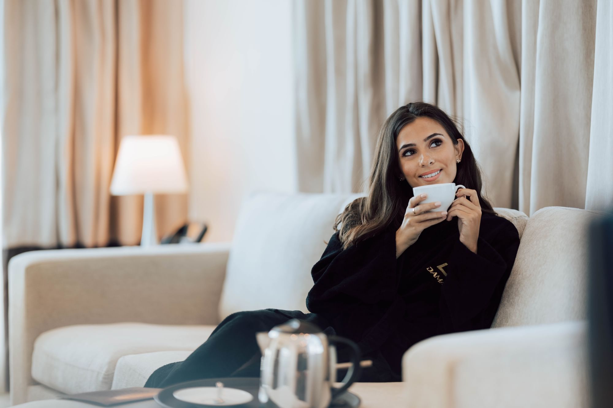A woman enjoying coffee in a lounge at Maison Royale The Distinction