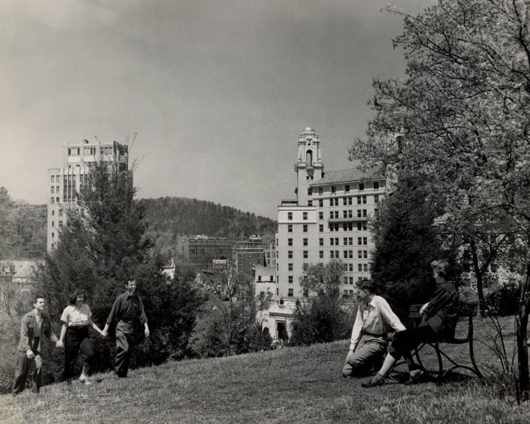 Guests by a wooden bench under a tree with a view of the towers at the historic Arlington Resort Hotel & Spa