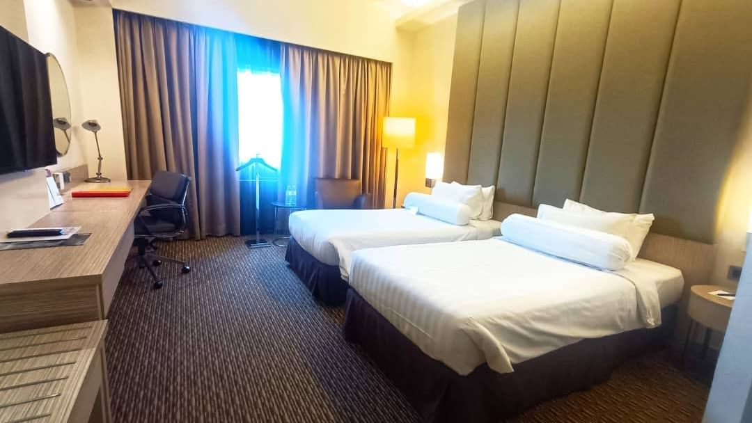 Premier Twin Room with two beds, a desk, and an armchair by the window at Sunway Hotel Seberang Jaya