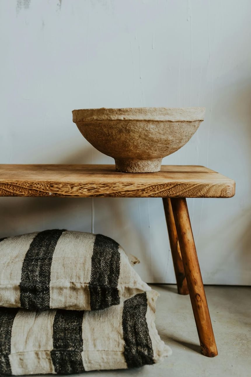 A bowl on a wooden bench with a striped cushion below the bench at Hotel Brookmere