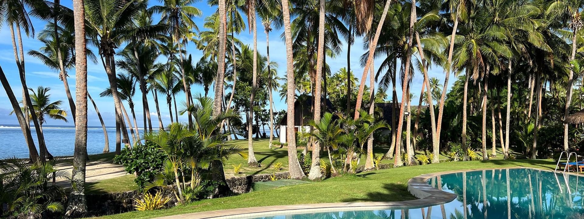 Clear pool surrounded by palm trees and lush greenery at Tambua Sands Beach Resort in Sigatoka