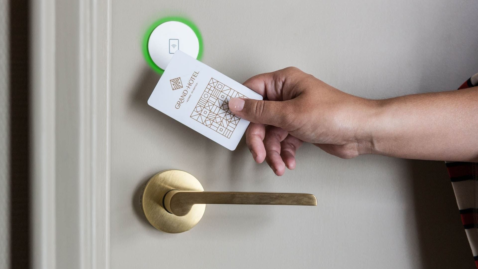 A person using an NFC key card to unlock a door at Bensaude Hotels