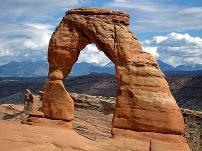 Delicate Arch in Arches National Park, set against scenic mountains and cloudy skies near Moab Valley Inn